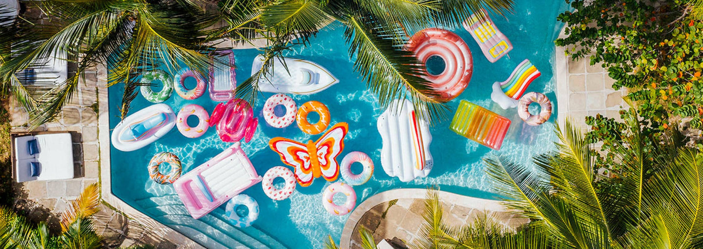 A variety of Funboy floats in a pool with trees. 